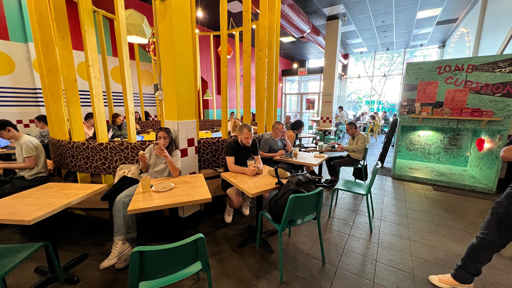 Inside of the La Graine Brûlée, bright yellow and mint green structures, occupied small tables.